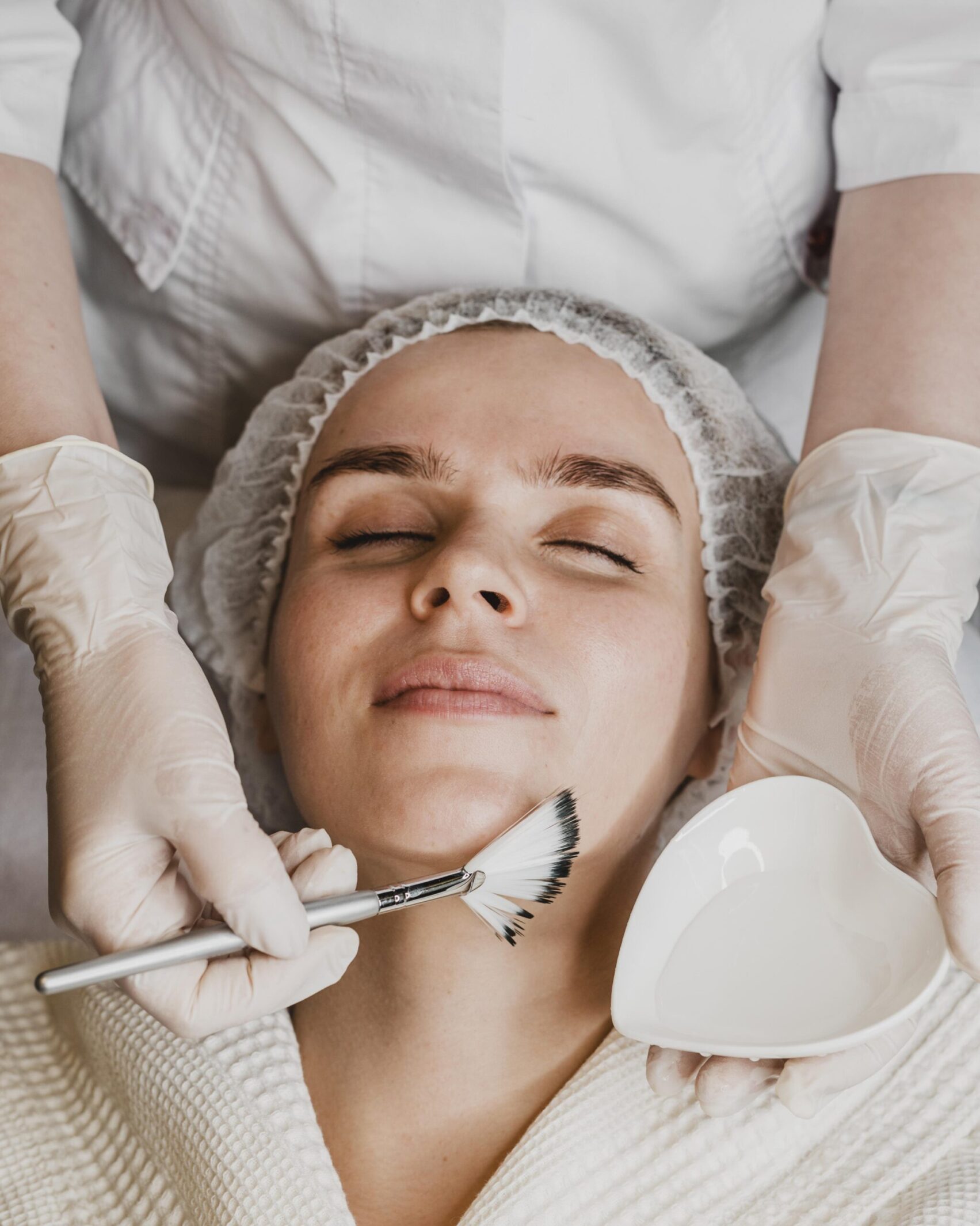 top view young beautiful woman getting face skin treatment